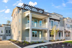 View of rear facade featuring covered porch, a garage, and a balcony