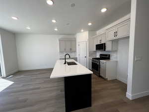 Kitchen with decorative backsplash, a kitchen island with sink, appliances with stainless steel finishes, hardwood / wood-style flooring, and sink