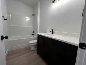 Full bathroom with hardwood / wood-style flooring, shower / bathtub combination, toilet, and vanity