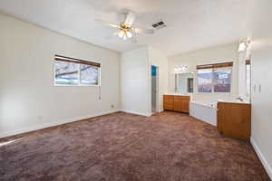 Unfurnished bedroom with multiple windows, sink, dark carpet, and a textured ceiling