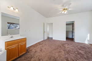 Interior space with sink, dark colored carpet, a walk in closet, ceiling fan, and a closet