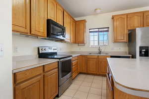 Kitchen with stainless steel appliances, sink, and light tile patterned floors