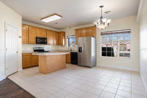 Kitchen featuring hanging light fixtures, a healthy amount of sunlight, a center island, and black appliances