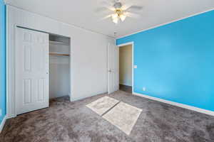 Unfurnished bedroom featuring carpet flooring, ceiling fan, and a closet