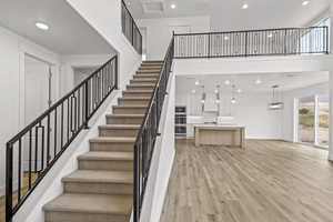 Staircase with light hardwood / wood-style flooring and a high ceiling