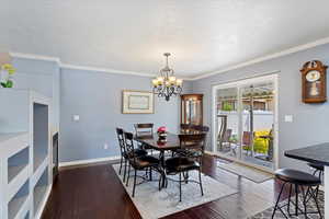 Dining space featuring an inviting chandelier, a textured ceiling, hardwood flooring, sider to backyard and crown molding.