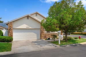 Front yard with attached garage, stone and vinyl exterior features.