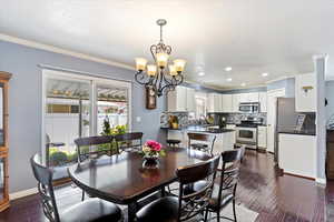 Dining space featuring an inviting chandelier, a textured ceiling, hardwood flooring, sider to backyard and crown molding.