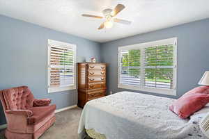 Carpeted bedroom with a textured ceiling and ceiling fan.