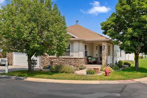 Front yard with attached garage, stone and vinyl exterior features and large front porch.