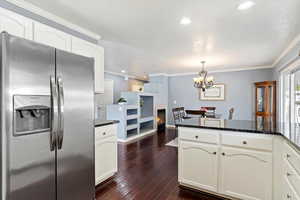 Kitchen with peninsula island , appliances with stainless steel finishes, backsplash, painted cabinets, corner pantry, and wood flooring.