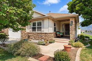 Front yard with attached garage, stone and vinyl exterior features and large front porch.