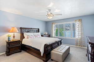 Carpeted bedroom featuring a textured ceiling and ceiling fan.