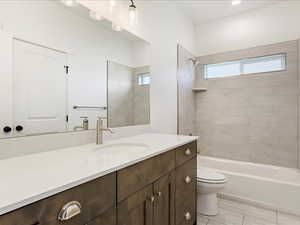 Full bathroom with tile patterned flooring, toilet, tiled shower / bath combo, and vanity