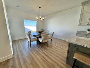 Dining area featuring light wood-type flooring, a textured ceiling, and an inviting chandelier