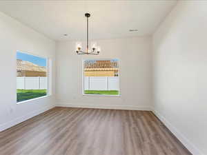 Empty room with light hardwood / wood-style floors and a notable chandelier