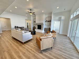 Living room with a textured ceiling, light hardwood / wood-style flooring, and ceiling fan