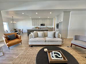 Living room featuring light wood-type flooring, a textured ceiling, sink, and an inviting chandelier