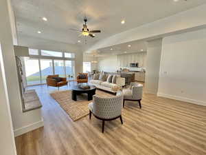 Living room with light hardwood / wood-style floors, ceiling fan with notable chandelier, and a textured ceiling