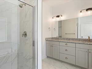 Bathroom featuring tile patterned flooring, vanity, and walk in shower