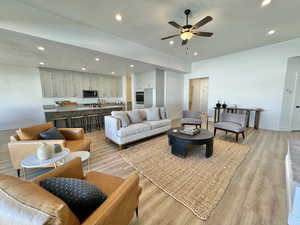 Living room with light wood-type flooring, a textured ceiling, sink, and ceiling fan