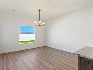 Unfurnished dining area featuring hardwood / wood-style flooring and a notable chandelier