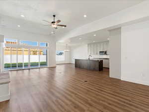 Unfurnished living room with ceiling fan with notable chandelier and wood-type flooring