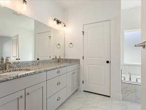 Bathroom with vanity, tiled bath, and tile patterned floors