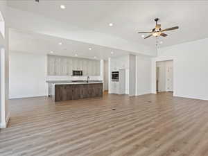 Unfurnished living room featuring ceiling fan, sink, and hardwood / wood-style flooring