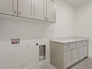 Laundry area with hookup for a washing machine, cabinets, electric dryer hookup, and hookup for a gas dryer