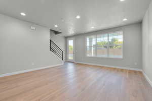 Unfurnished living room featuring a textured ceiling and light hardwood / wood-style floors