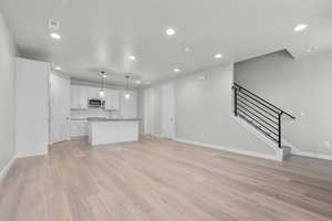 Unfurnished living room featuring sink and light wood-type flooring