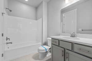 Full bathroom featuring toilet, vanity, tile patterned floors, and washtub / shower combination