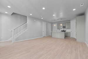 Unfurnished living room featuring sink and light hardwood / wood-style floors