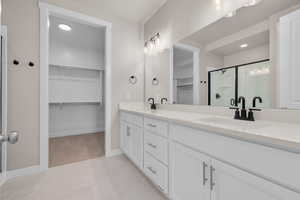 Bathroom featuring vanity, a shower with shower door, and tile patterned floors