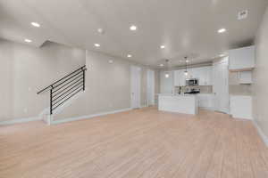 Unfurnished living room featuring a textured ceiling, sink, and light wood-type flooring