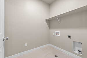 Laundry area featuring electric dryer hookup, washer hookup, and light tile patterned flooring