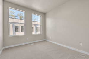 Empty room featuring a textured ceiling and light colored carpet