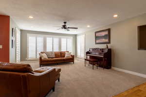 Living room with a textured ceiling, light hardwood / wood-style flooring, and ceiling fan