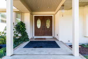 Doorway to property featuring covered porch