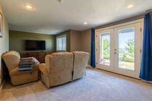 Living room with light colored carpet, a textured ceiling, and french doors