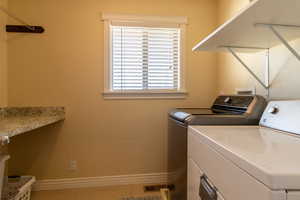 Laundry area featuring separate washer and dryer, tile patterned floors, and plenty of natural light