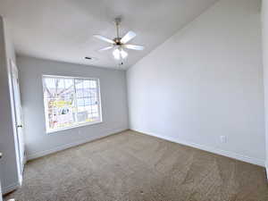 Empty room featuring carpet, ceiling fan, and vaulted ceiling