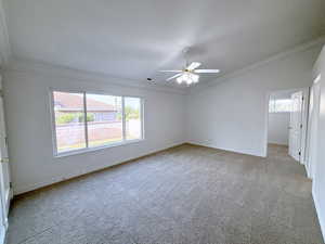 Spare room with lofted ceiling, light carpet, ornamental molding, and ceiling fan