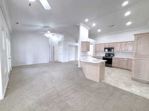 Kitchen with electric range, light carpet, ceiling fan, and light brown cabinets