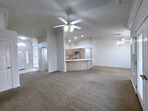 Unfurnished living room featuring ceiling fan, lofted ceiling, light colored carpet, and ornamental molding