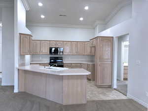 Kitchen featuring stainless steel appliances, sink, light brown cabinets, kitchen peninsula, and light carpet