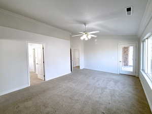 Carpeted spare room with lofted ceiling, crown molding, and ceiling fan