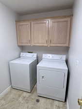 Laundry room featuring independent washer and dryer, cabinets, and light tile patterned floors