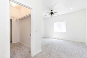 Interior space with light carpet, a closet, ceiling fan, and a walk in closet